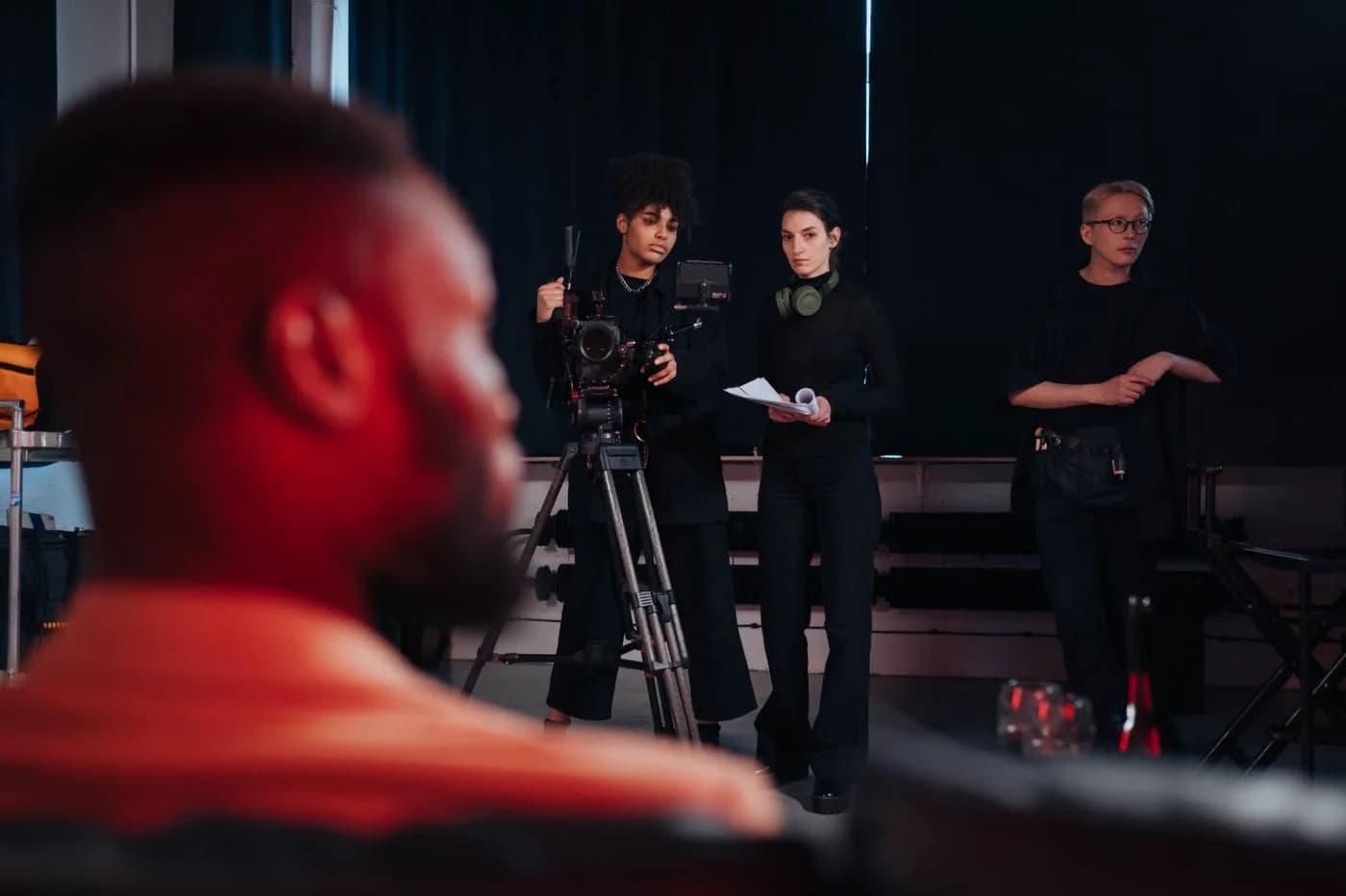 Film crew coordinating a studio shoot behind a professional cinema camera