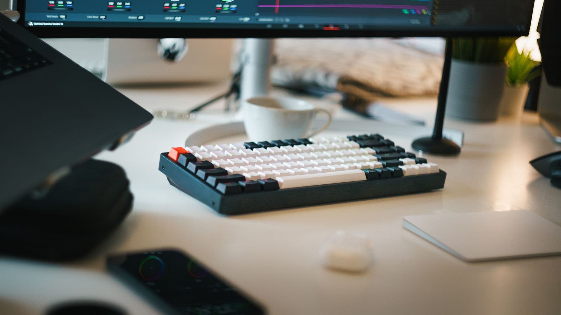 A keyboard, headphones, and graphics tablet sit below a video editing monitor.