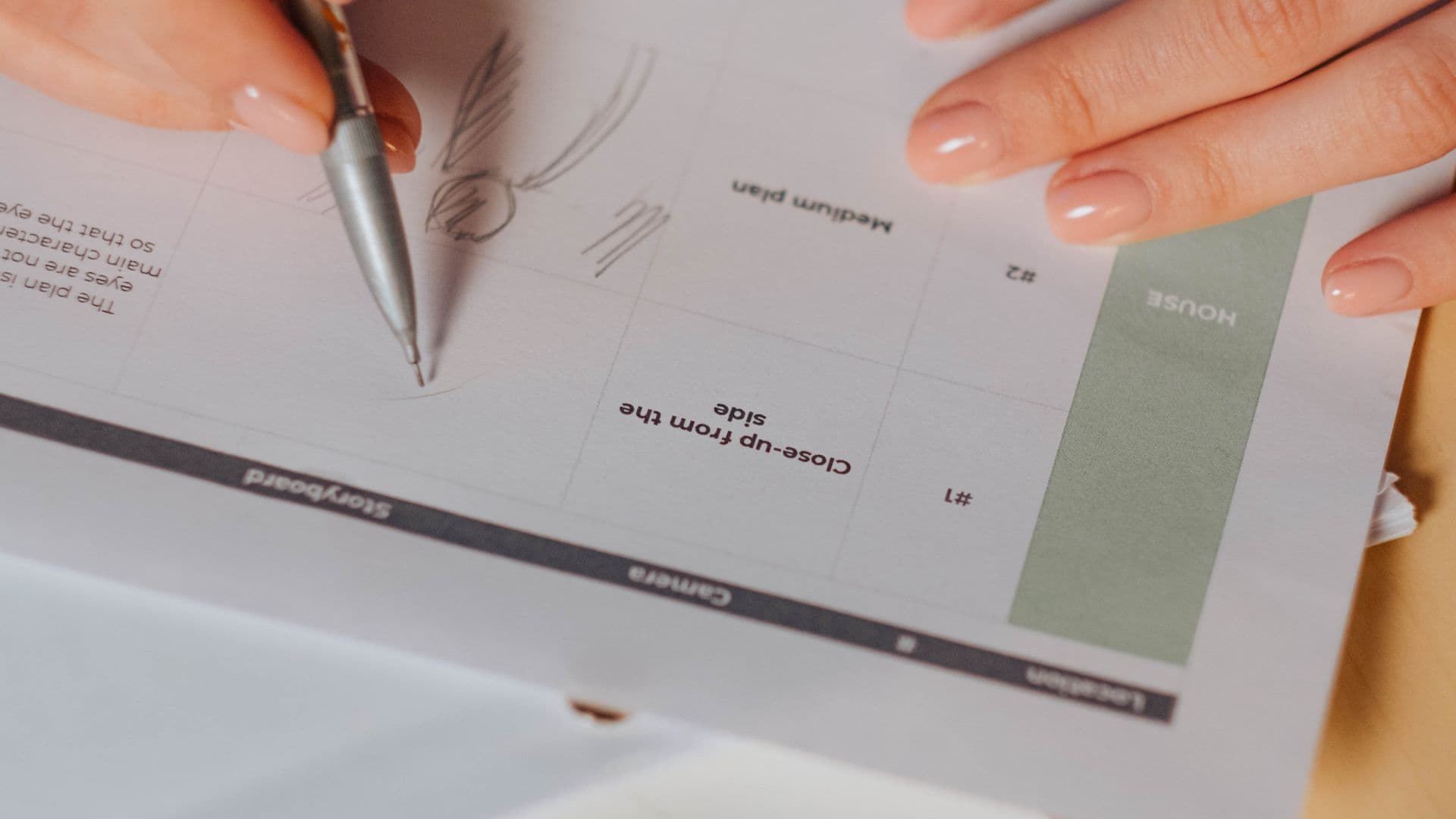 A hand sketches a character on a printed storyboard sheet.